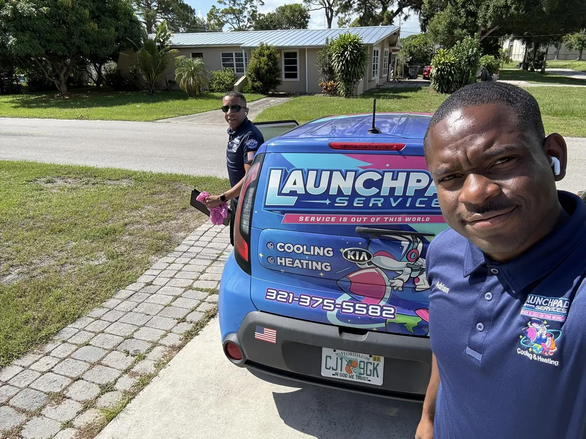 A smiling Launchpad Services technician next to a branded service vehicle in Palm Bay