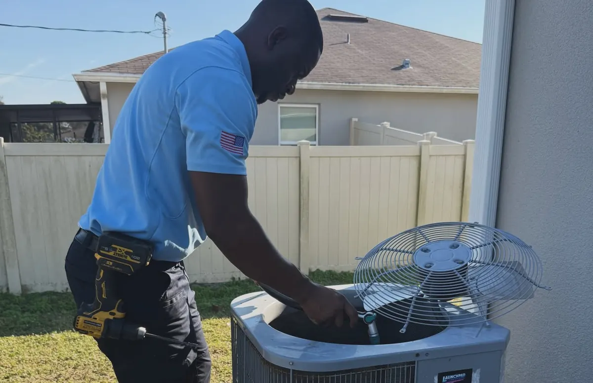 Launchpad Services technician performing an AC tune-up on a condenser at a Palm Bay home